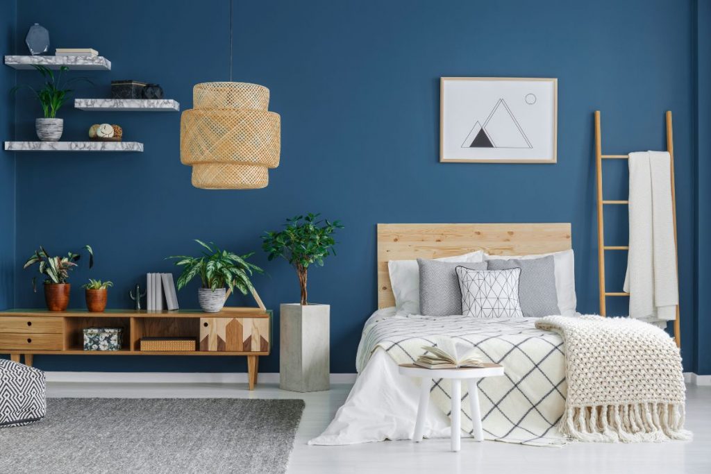 Dormitorio de matrimonio estilo nórdico con la pared azul y muebles en pino natural